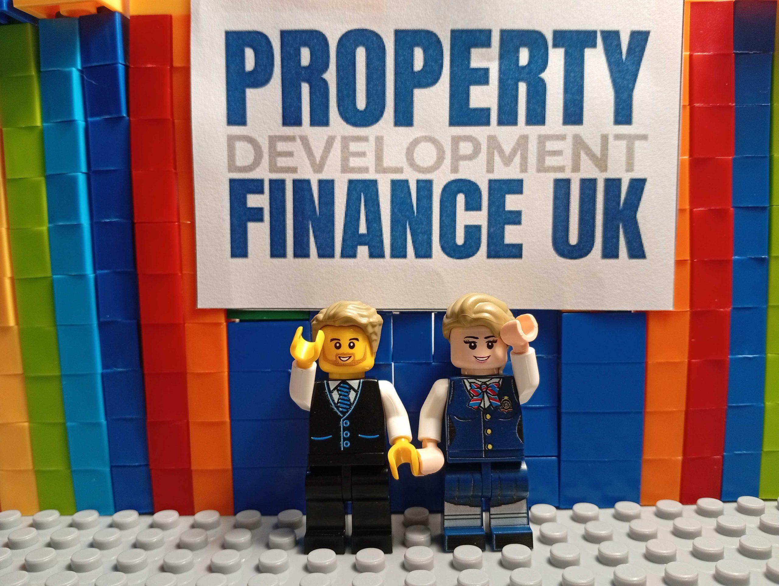property-development-finance-connect-page-hero-image Two Lego-style advanced developer characters waving in front of Property Development Finance UK branding on the Connect page